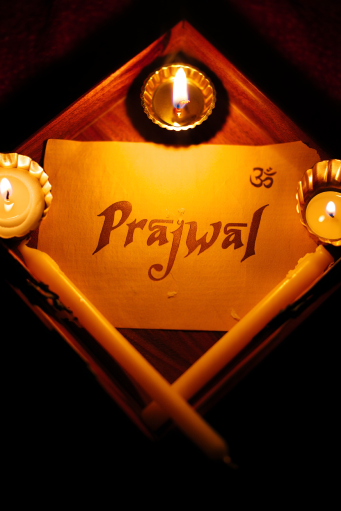 Prajwal written in Sanskrit script with glowing light and diya symbolizing radiance and spiritual meaning.